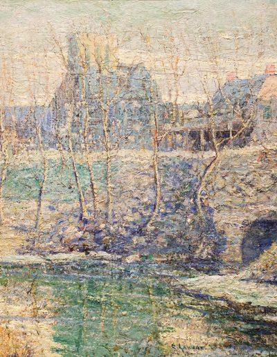 A small frozen pond in the foreground with several thin trees with bare branches on its shore in the middle. Two large buildings are obscured in the background.